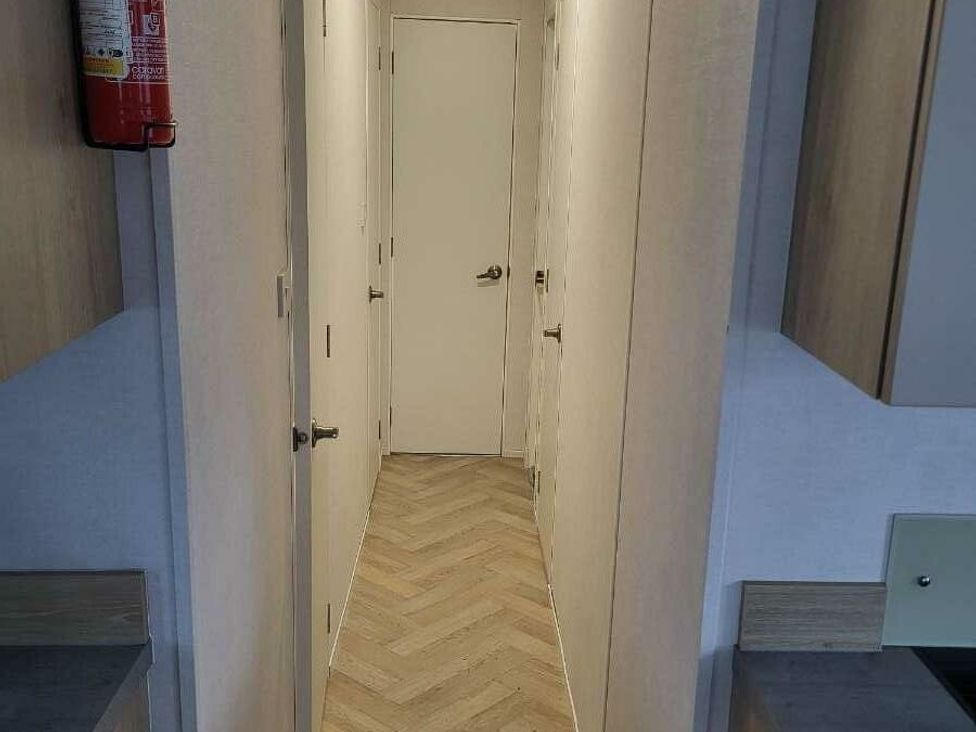 a hallway with a wooden floor and white doors at Ty Mawr Holiday Park - Holiday Accommodation 21121, Ty Mawr