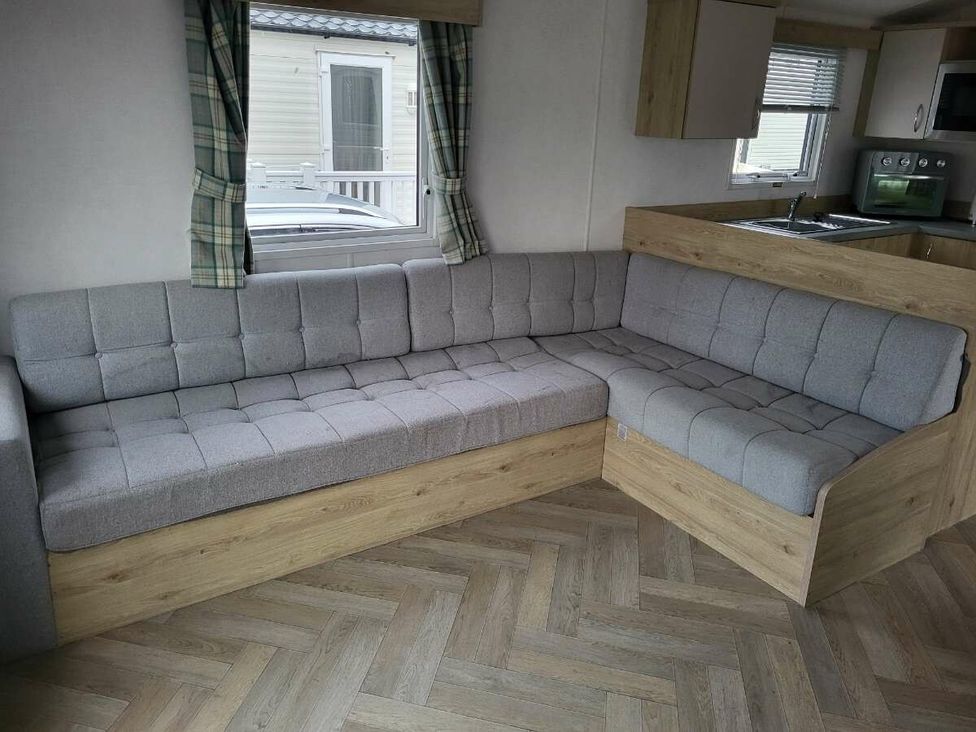 a gray corner sofa in a living room with wooden accents at Ty Mawr Holiday Park - Holiday Accommodation 21121 in Ty Mawr