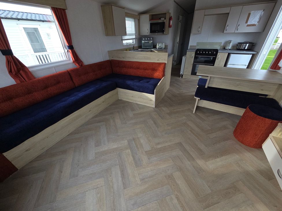 A living room with a sofa, table, and kitchen unit at Ty Mawr Holiday Park - Holiday Accommodation 21121 in Ty Mawr