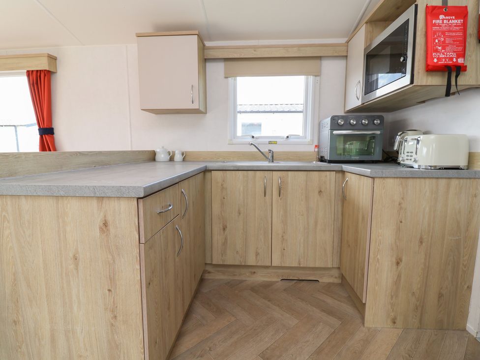 A kitchen with cabinets, sink, microwave, and kettle at Ty Mawr Holiday Park - Holiday Accommodation 21121 Ty Mawr
