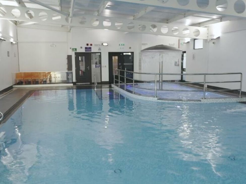 an indoor swimming pool with a raised area and a seating space at Whitehouse Leisure Park - Holiday Accommodation 21355 Towyn