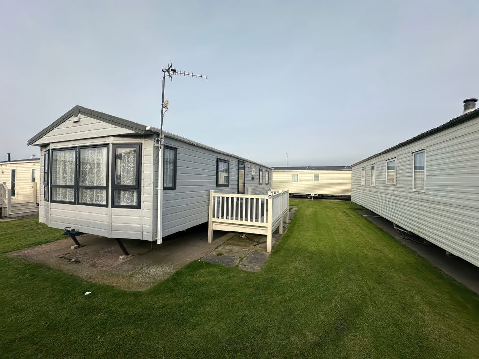 A caravan with a small deck outside in an outdoor area at Whitehouse Leisure Park - Holiday Accommodation 21355 Towyn