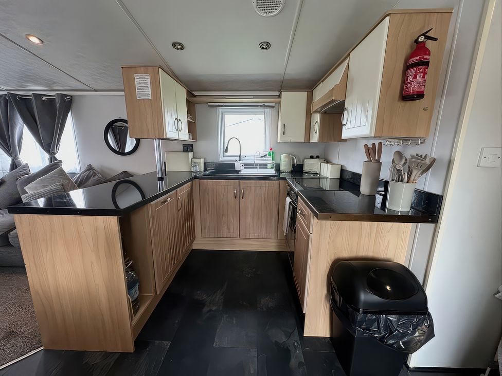 A kitchen with cabinets, appliances, and a sink at Whitehouse Leisure Park - Holiday Accommodation 21355 Towyn