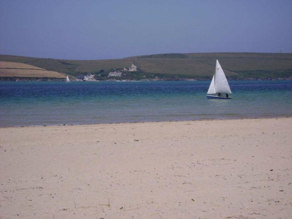 a beach with sand and a sailboat on the water at St Minver Holiday Park - Holiday Accommodation 21443 in Wadebridge