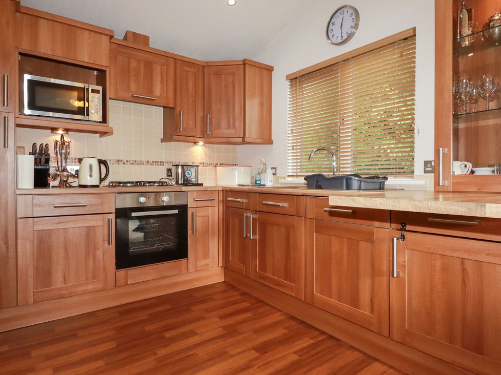 A kitchen with wooden cabinets and appliances at St Minver Holiday Park - Holiday Accommodation 21443 Wadebridge