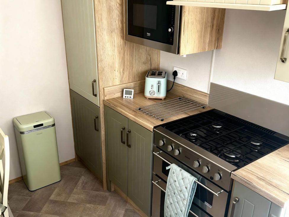 A kitchen with appliances and cabinets at Aberdunant Hall Holiday Park - Holiday Accommodation 21962 in Prenteg