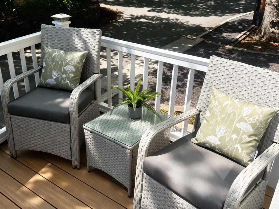 An outdoor seating area with chairs and a side table at Aberdunant Hall Holiday Park - Holiday Accommodation 21962, Prenteg