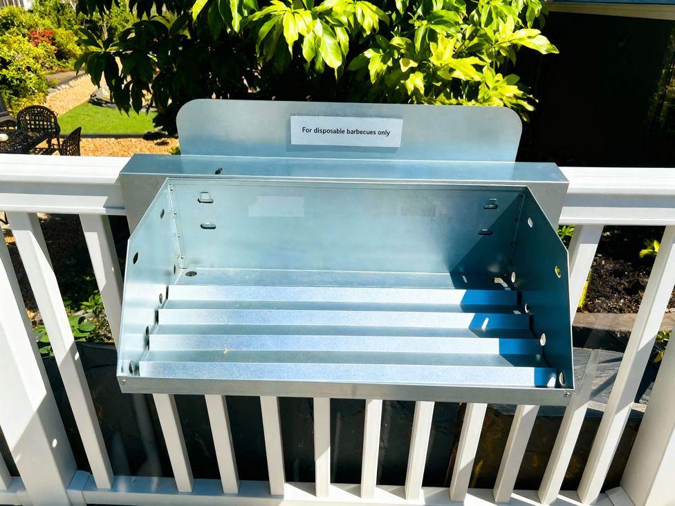 A metal holder for disposable barbecues in an outdoor setting at Aberdunant Hall Holiday Park - Holiday Accommodation 21962 Prenteg