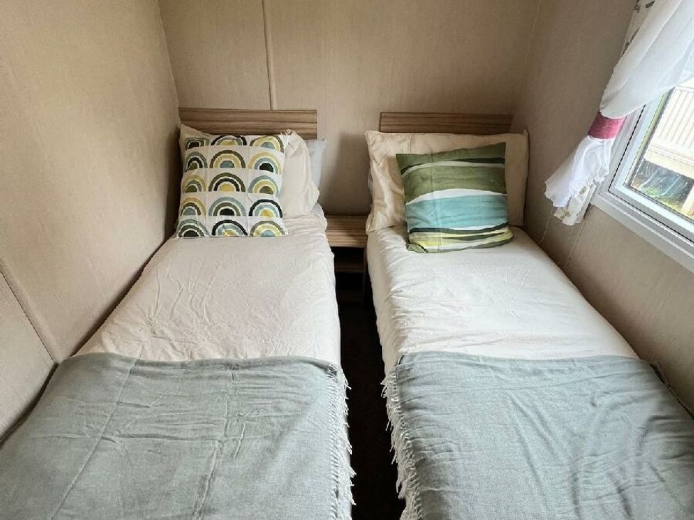 a bedroom with two single beds, one with a patterned pillow and the other with a striped pillow at Hoburne Devon Bay - Holiday Accommodation 22090, Paignton