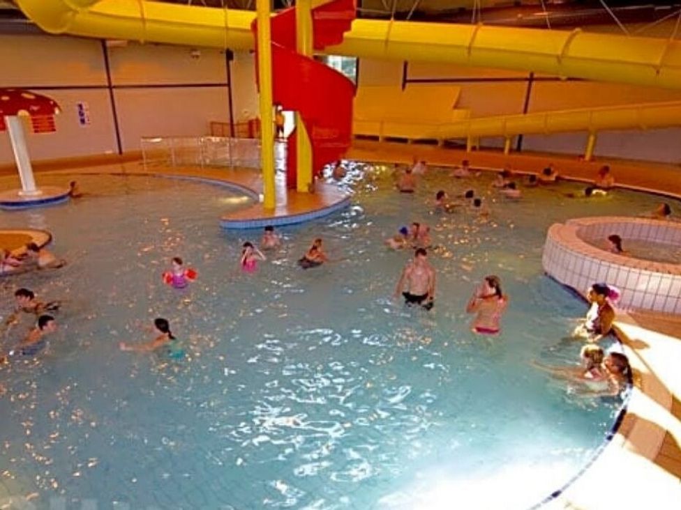 an indoor swimming pool with a water slide and people swimming at Hoburne Devon Bay - Holiday Accommodation 22090 in Paignton