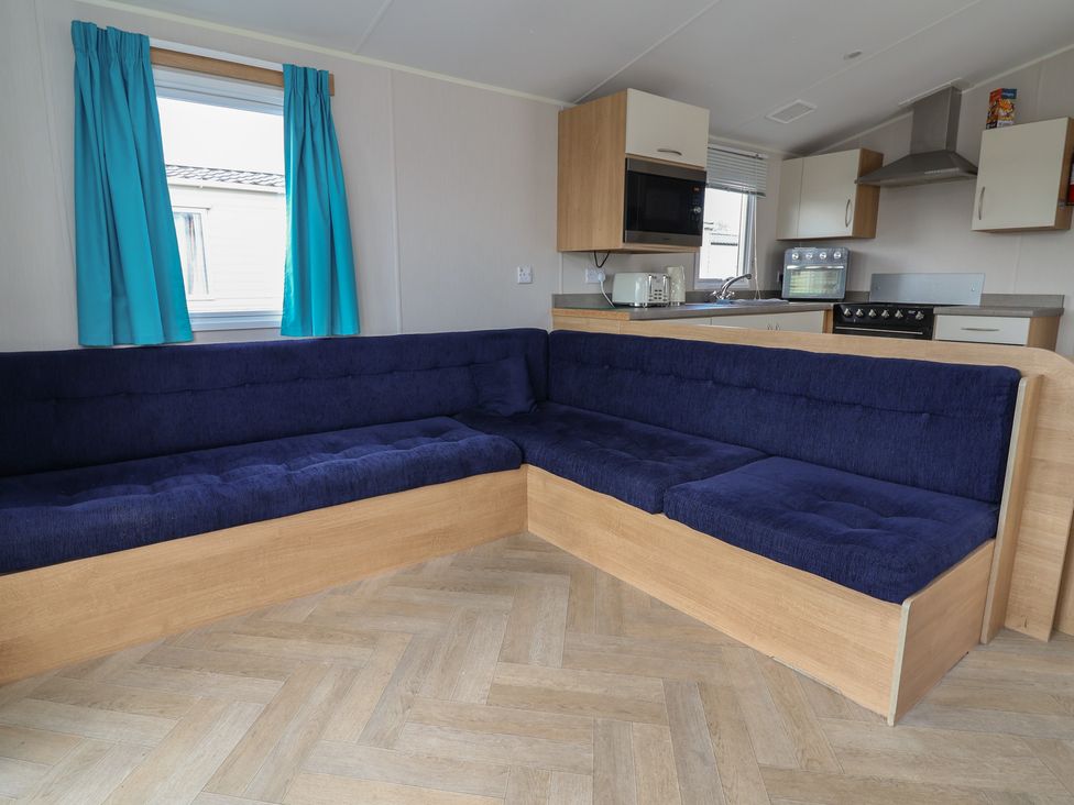 A living room with a corner sofa and kitchen unit at Ty Mawr Holiday Park - Holiday Accommodation 22393, Towyn