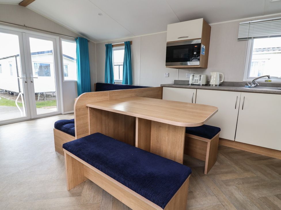 A dining room with a table and benches at Ty Mawr Holiday Park - Holiday Accommodation 22393 Towyn