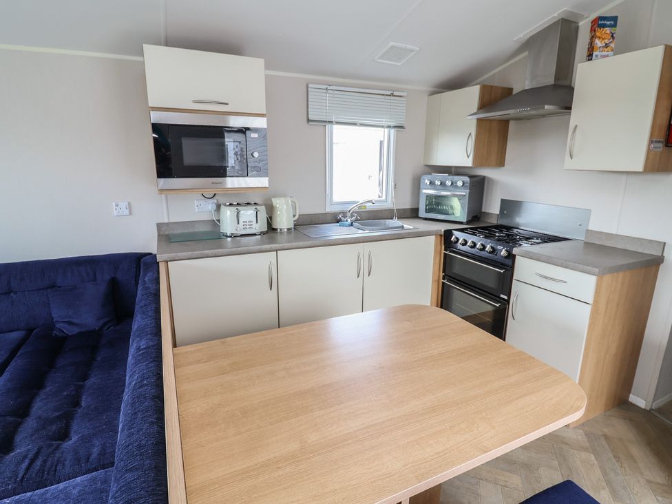 A kitchen with appliances and a table at Ty Mawr Holiday Park - Holiday Accommodation 22393 Towyn