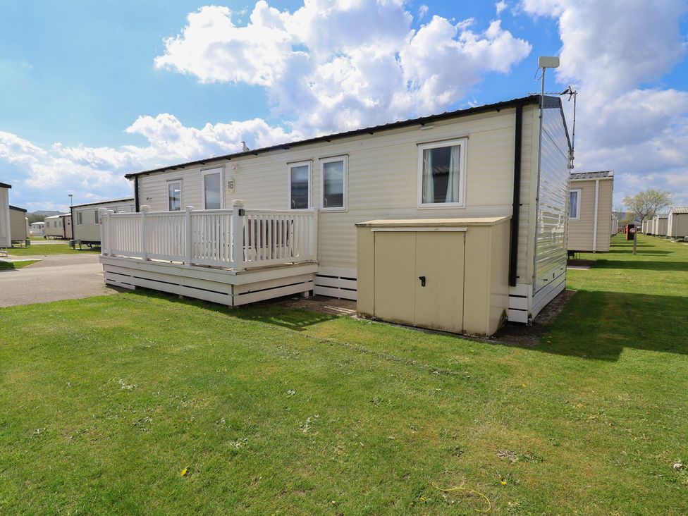 A mobile home with a deck and storage shed at Ty Mawr Holiday Park - Holiday Accommodation 22393 Towyn