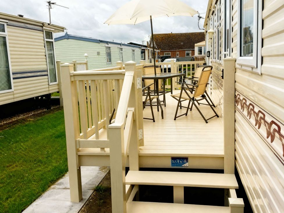 An outdoor area with a deck, table, and chairs at Coastfield Holiday Village - Holiday Accommodation 2604 Ingoldmells