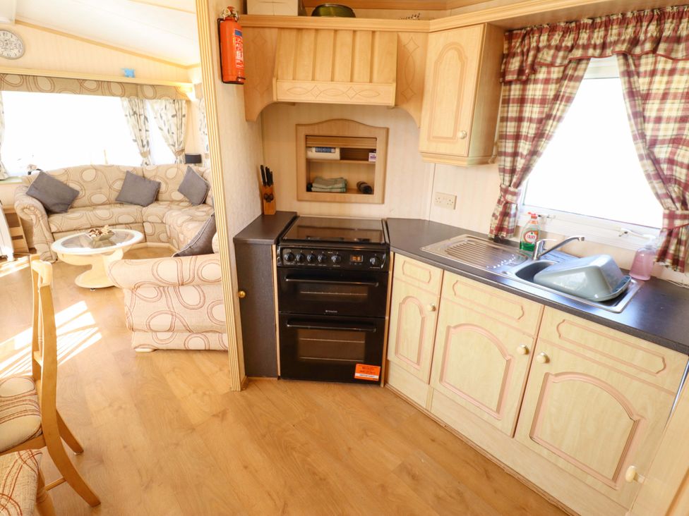 A living room with sofa and kitchen area at Coastfield Holiday Village - Holiday Accommodation 2604 in Ingoldmells