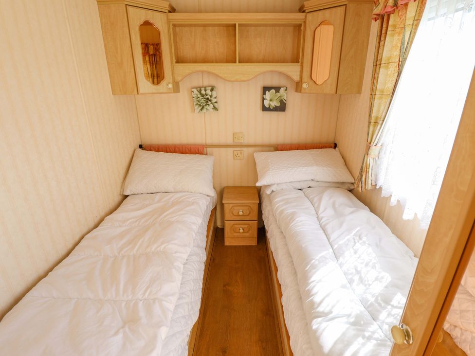 A bedroom with two beds and a bedside table at Coastfield Holiday Village - Holiday Accommodation 2604 in Ingoldmells