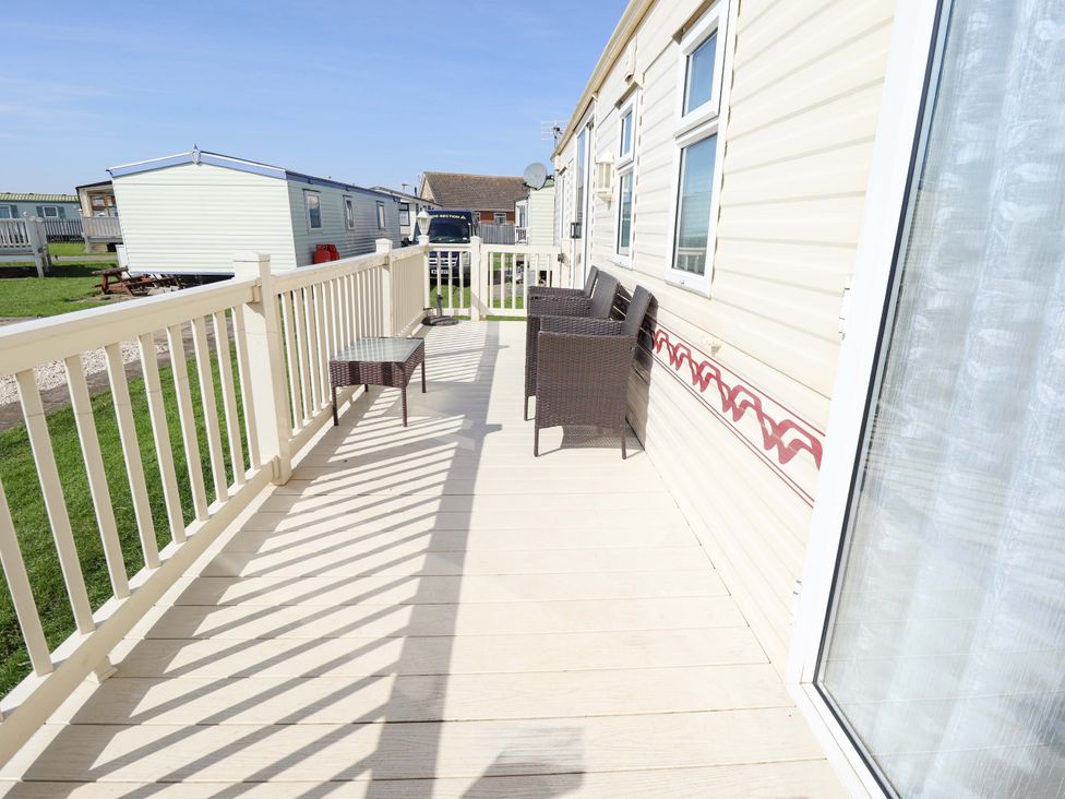 A deck with chairs and a table at Coastfield Holiday Village - Holiday Accommodation 2604 Ingoldmells