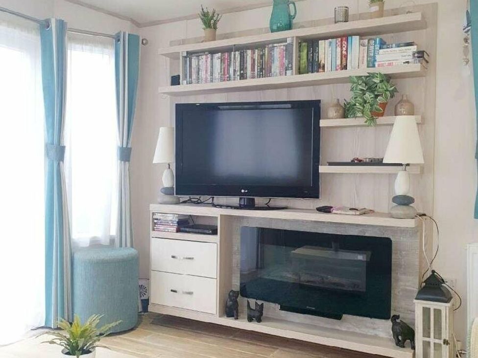 a living room with a TV and shelves containing books at Shorefield Country Park - Holiday Accommodation 3042 in Milford On Sea