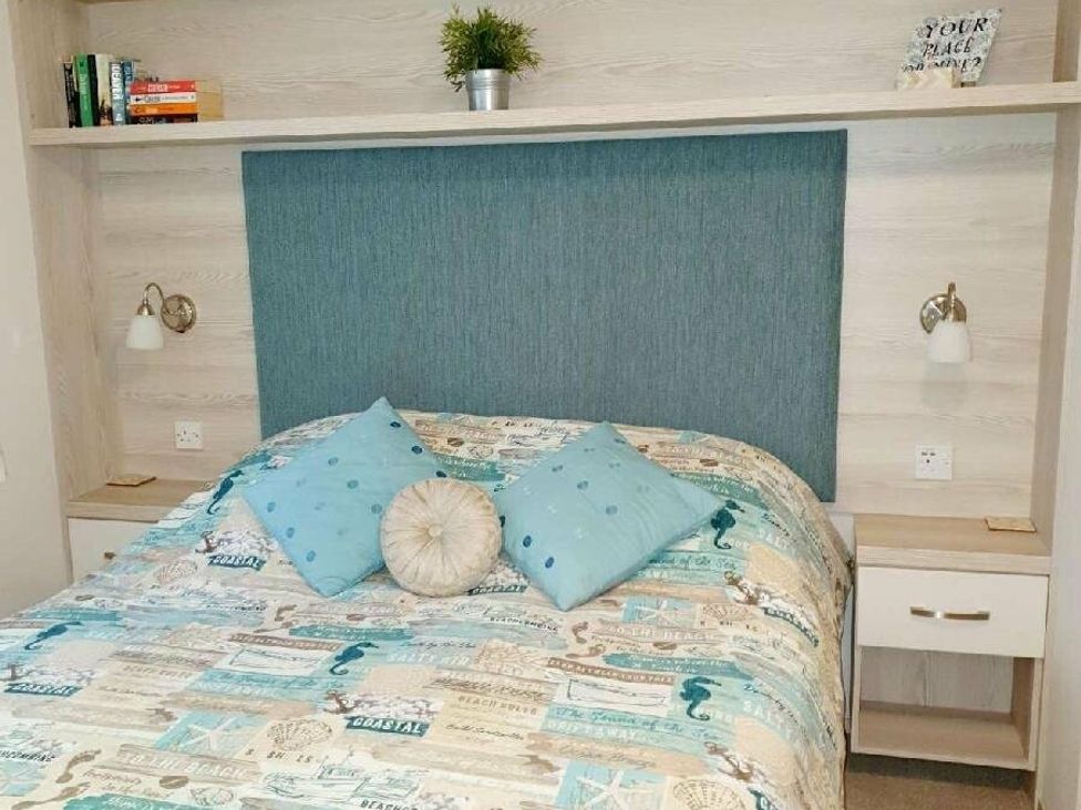 a bedroom with a blue headboard and patterned bedding at Shorefield Country Park - Holiday Accommodation 3042 Milford On Sea