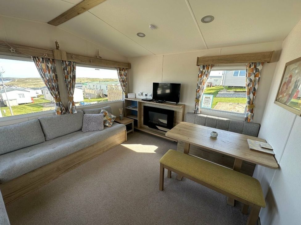 a living room with a sofa, table, and TV at Liskey Hill Caravan Park - Holiday Accommodation 3043 Perranporth