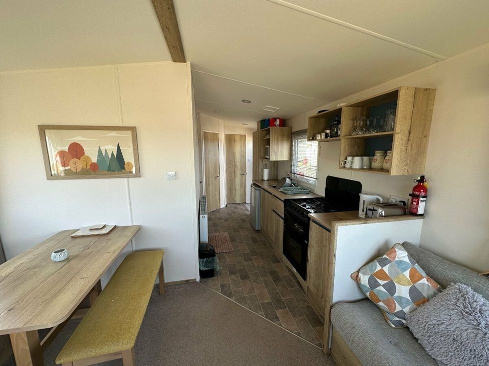 a kitchen area with a dining table and a sofa at Liskey Hill Caravan Park - Holiday Accommodation 3043 Perranporth