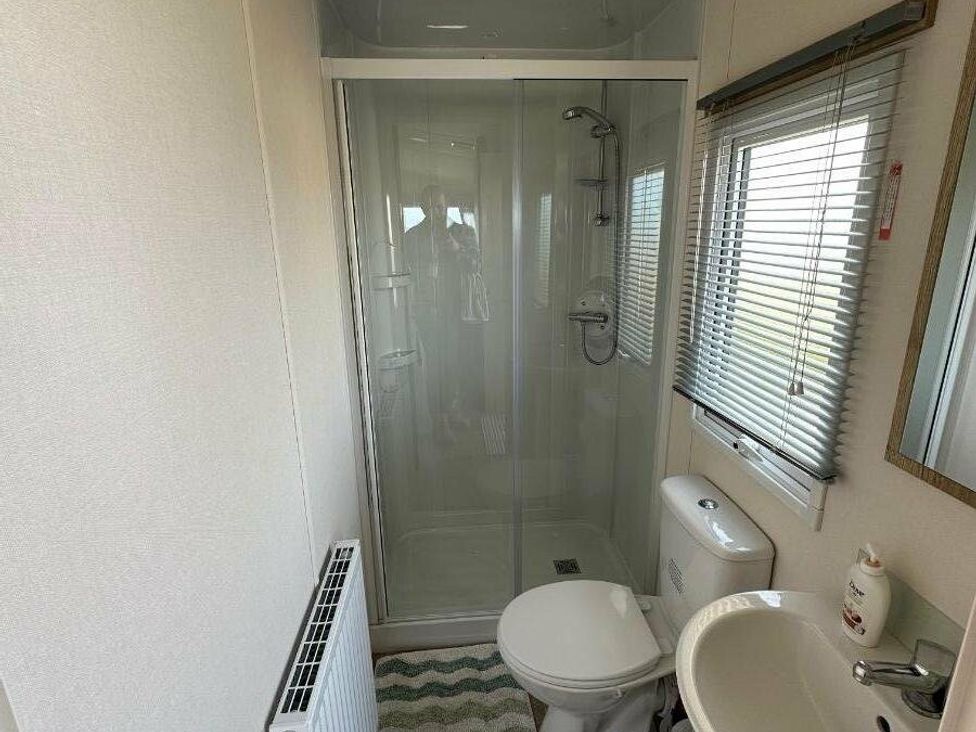 a bathroom with a shower, toilet, and sink at Liskey Hill Caravan Park - Holiday Accommodation 3043, Perranporth