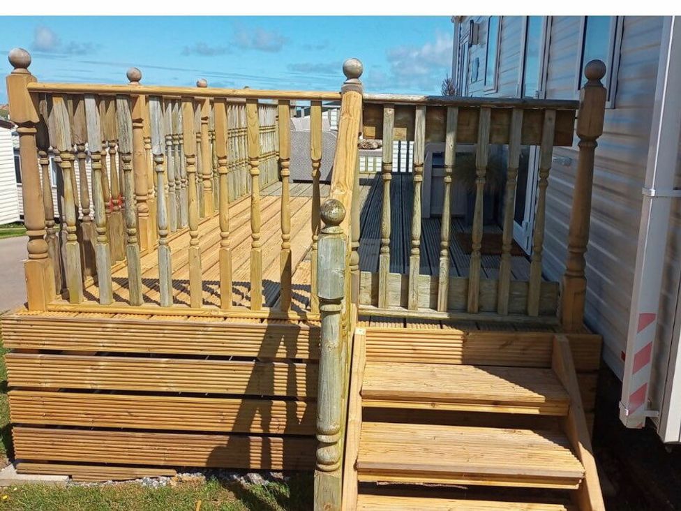 a wooden deck with railings and steps at Liskey Hill Caravan Park - Holiday Accommodation 3043 Perranporth