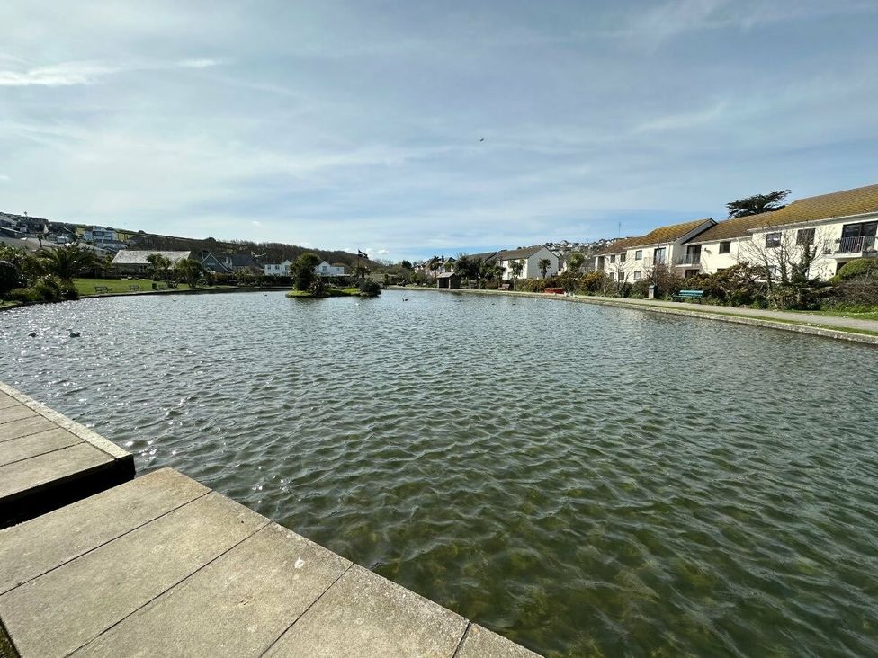 a body of water surrounded by greenery and buildings at Liskey Hill Caravan Park - Holiday Accommodation 3043, Perranporth