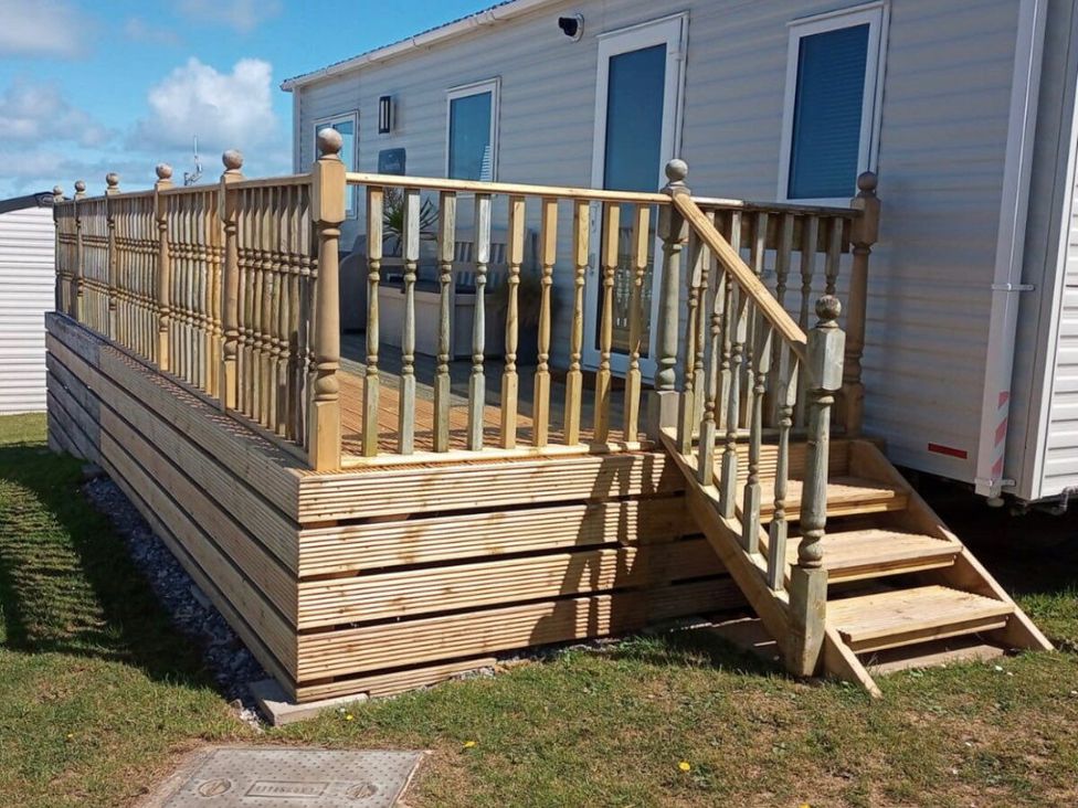 a wooden deck with railings and stairs outside a caravan at Liskey Hill Caravan Park - Holiday Accommodation 3043, Perranporth