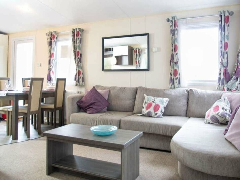 a living room with a sectional sofa, dining table, and decorative cushions at Shorefield Country Park - Holiday Accommodation 4132, Milford On Sea