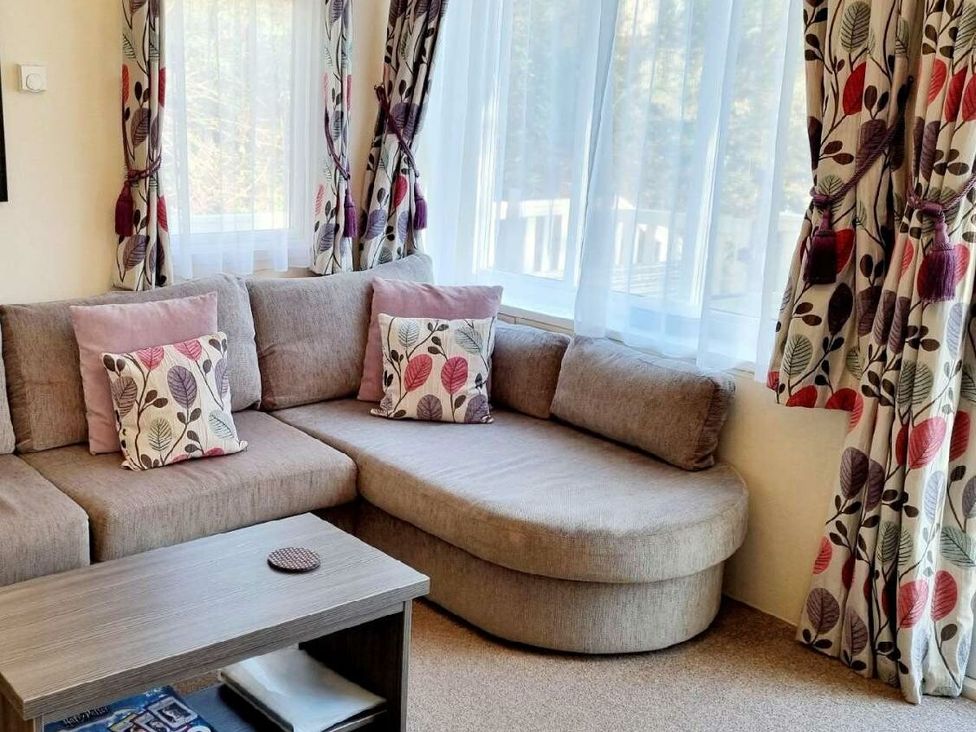 a seating area with a sectional sofa and decorative cushions at Shorefield Country Park - Holiday Accommodation 4132 in Milford On Sea