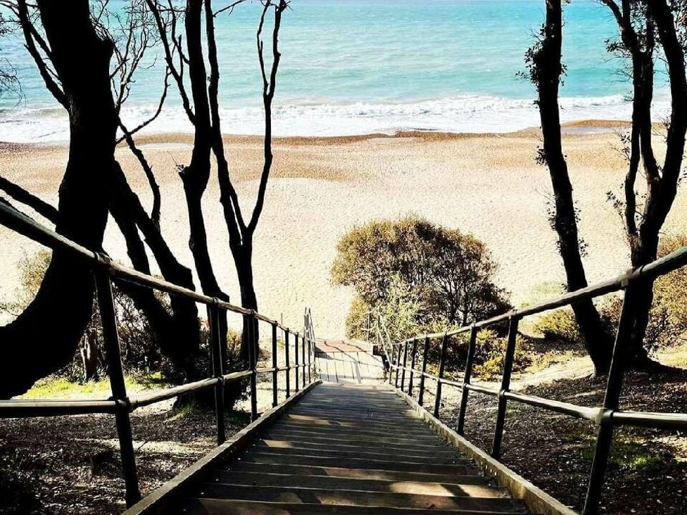 a wooden staircase leading down to a beach with trees on either side at Shorefield Country Park - Holiday Accommodation 4132 in Milford On Sea