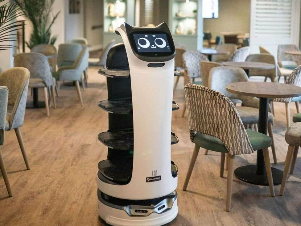 a robotic waiter in a dining area with tables and chairs at Shorefield Country Park - Holiday Accommodation 4132, Milford On Sea