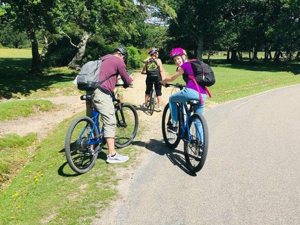 three people riding bicycles on a pathway in a grassy area at Shorefield Country Park - Holiday Accommodation 4132 Milford On Sea