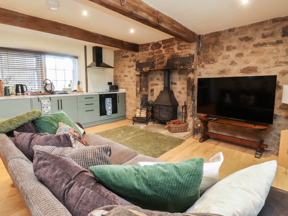 A living room with a fireplace and kitchen cabinets at The Snug in Morecambe
