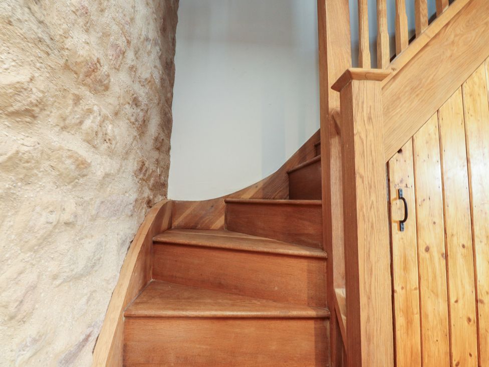 A staircase with wooden steps and a stone wall at The Snug in Morecambe