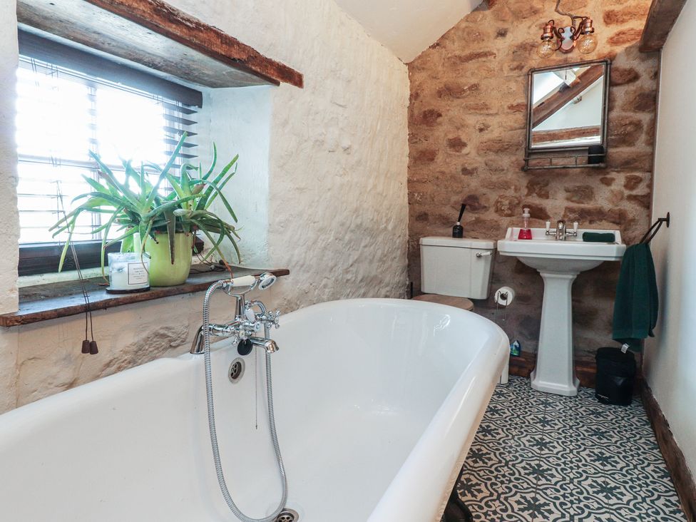 A bathroom featuring a bath tub, sink, and toilet at The Snug in Morecambe