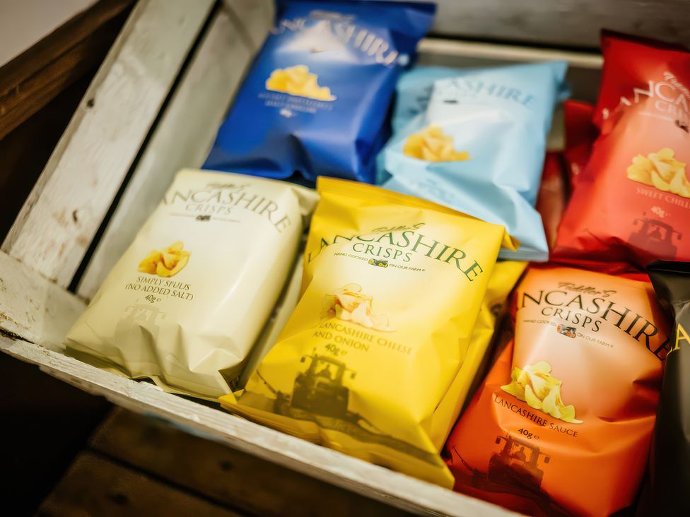 A selection of Lancashire crisps in various flavors in a wooden box