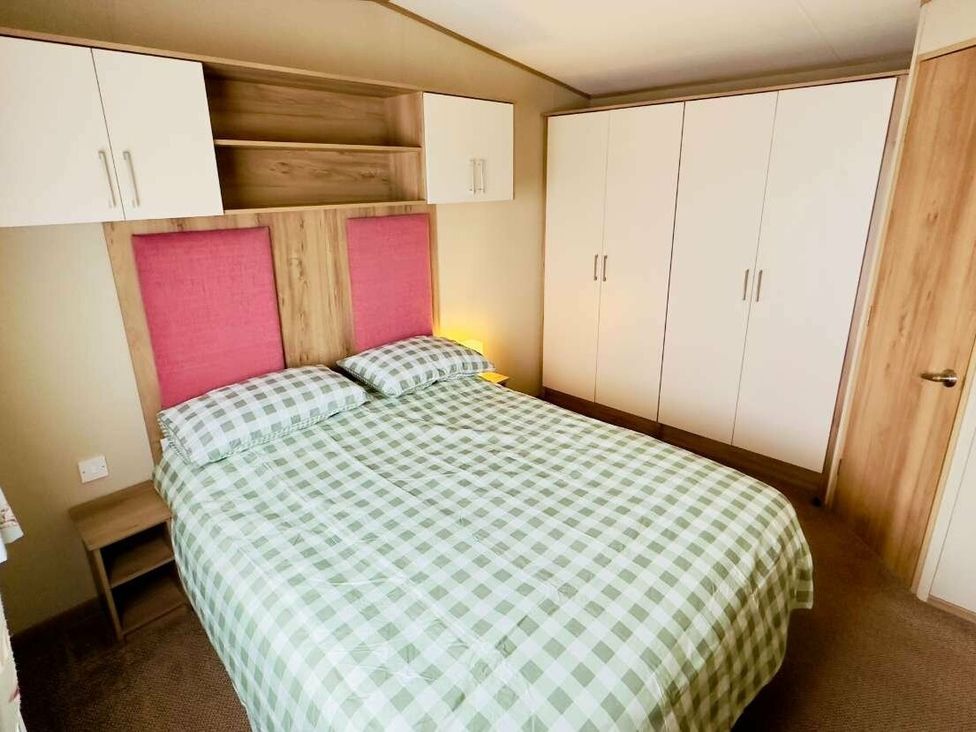 a bedroom with a double bed, headboard with pink panels, white wardrobes and shelves at St Andrews Holiday Park - Holiday Accommodation 609 St. Andrews