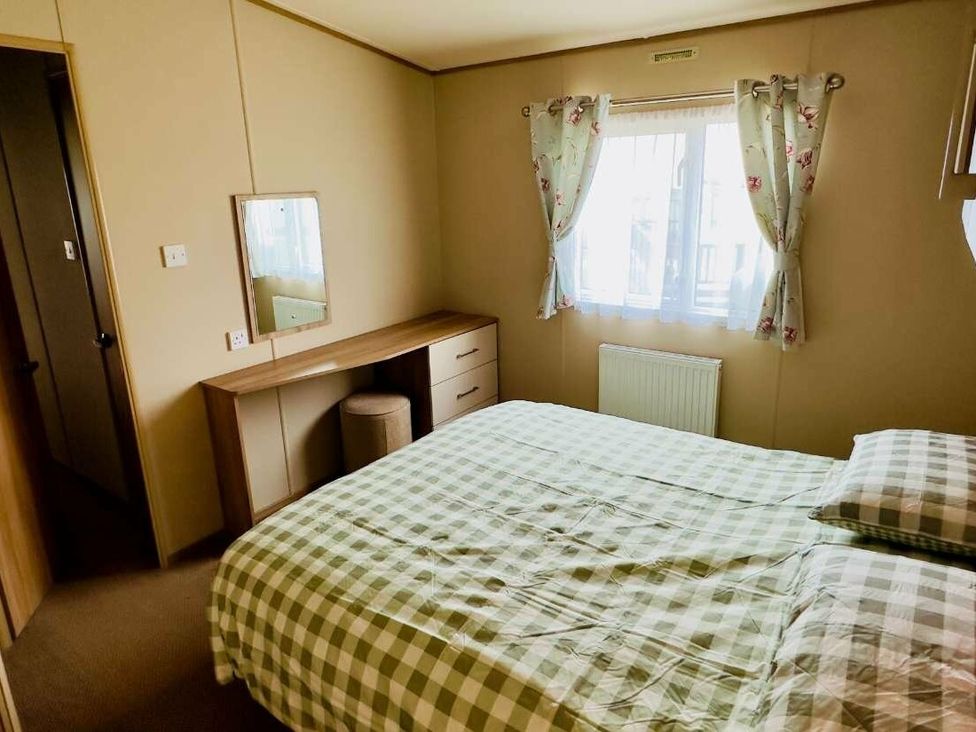 a bedroom with a checkered bedspread, a mirror, and a desk at St Andrews Holiday Park - Holiday Accommodation 609 St. Andrews