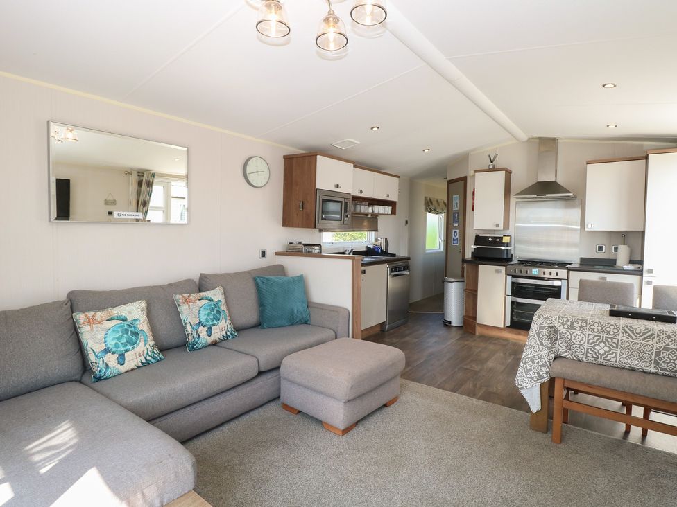 A living room with a sofa, dining table, and kitchen area at Hopton Holiday Village - Holiday Accommodation 632, Hopton-On-Sea