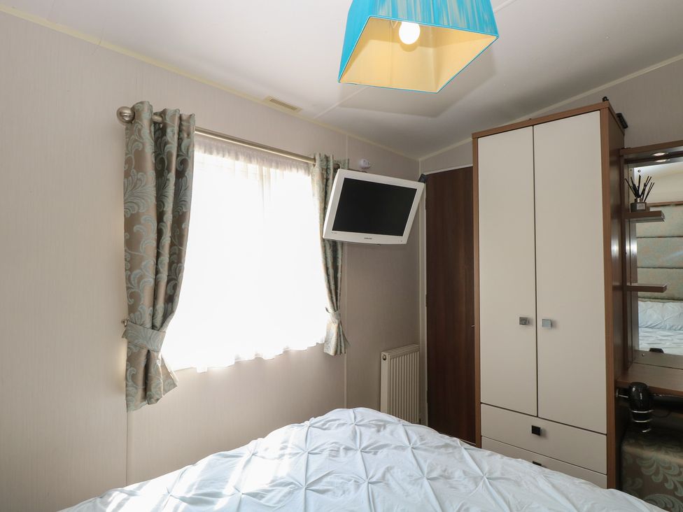 A bedroom with a bed, wardrobe, mirror, and television at Hopton Holiday Village - Holiday Accommodation 632 Hopton-On-Sea
