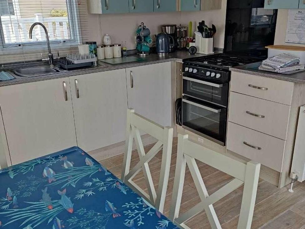 a kitchen with a sink, stove, and a table with a blue tablecloth at Durdle Door Holiday Park - Holiday Accommodation 6617, Wareham