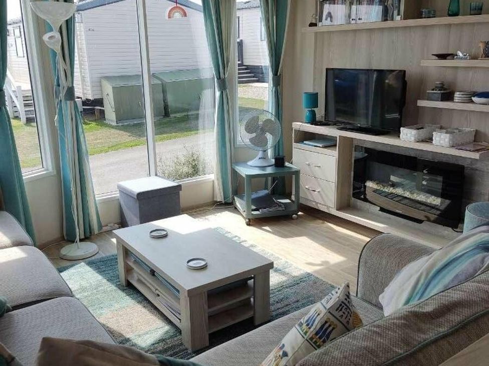 a living room with a television, sofa, and window at Durdle Door Holiday Park - Holiday Accommodation 6617, Wareham