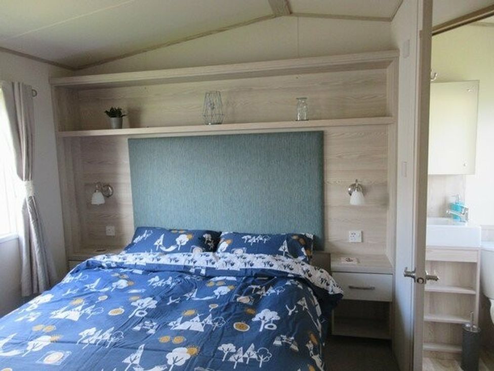 a bedroom with a bed featuring a blue patterned duvet at Durdle Door Holiday Park - Holiday Accommodation 6617, Wareham