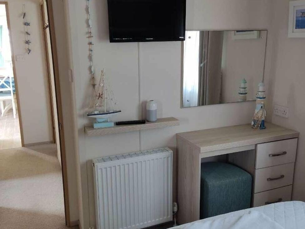a bedroom with a TV, mirror, desk, and a radiator at Durdle Door Holiday Park - Holiday Accommodation 6617, Wareham