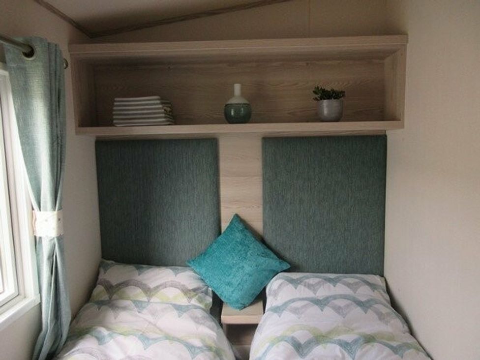 a bedroom with two single beds, a shelf above with decor at Durdle Door Holiday Park - Holiday Accommodation 6617, Wareham