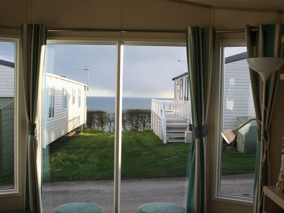 a view of the sea through a large window in a caravan at Durdle Door Holiday Park - Holiday Accommodation 6617 Wareham