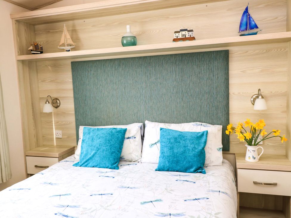 A bedroom with a bed and decorative items at Beachcombers in Wareham